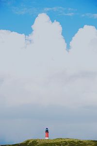 Lighthouse on field against sky