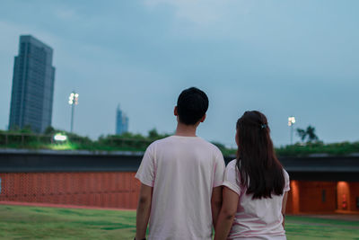 Rear view of couple standing in city against sky