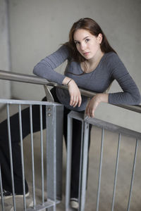 Portrait of woman standing against railing