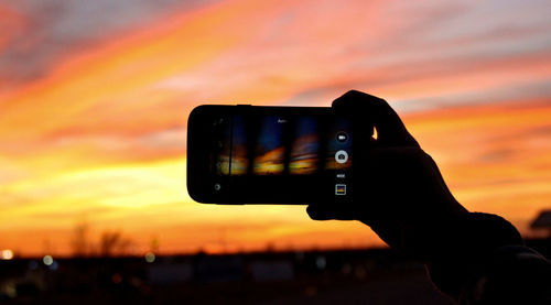Man photographing through smart phone at sunset