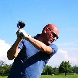 Low angle view of man playing soccer against blue sky