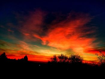 Silhouette trees against dramatic sky during sunset