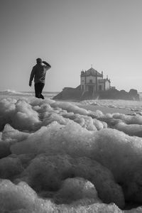 Rear view of man standing in front of church at beach