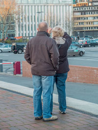 Rear view of couple walking on city street during winter
