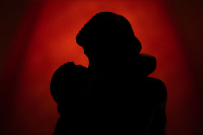 Close-up portrait of silhouette man standing against red wall