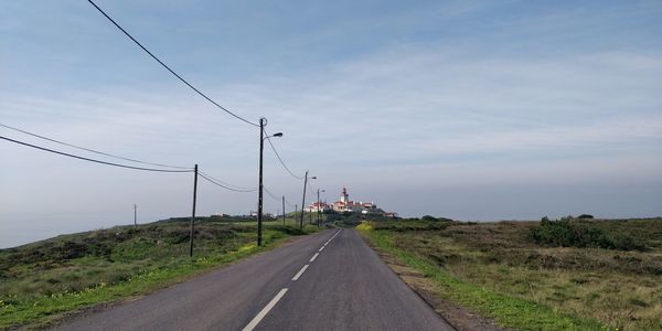 Road passing through land against sky