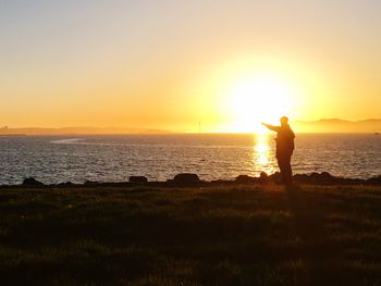 Silhouette man standing on beach against sky during sunset