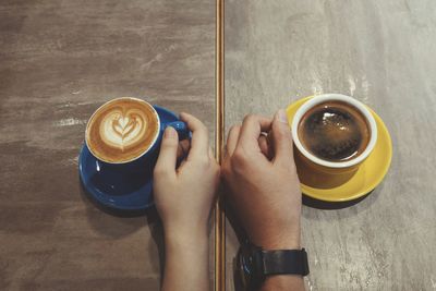 High angle view of man holding coffee cup on table