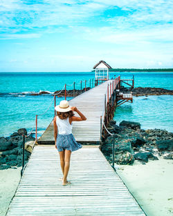 Rear view of woman walking on pier at beach