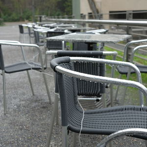 Empty chairs and tables at sidewalk cafe against building