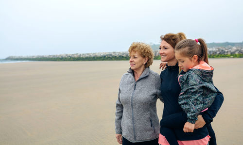 Smiling women and girl walking on beach