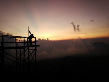 Silhouette of person on landscape against sunset sky