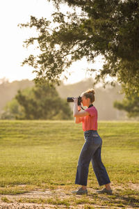 Full length of boy photographing while standing on land