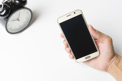 Close-up of hand holding mobile phone over white background