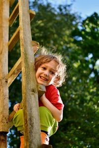 Portrait of boy on ladder against trees