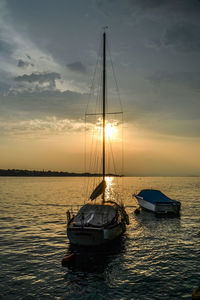 Sailboat moored in sea against sky during sunset
