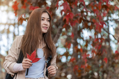 Portrait of young woman standing against trees