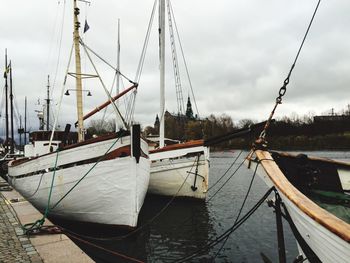 Sailboats moored on shore against sky