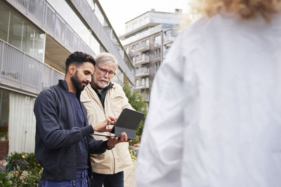 Two men with laptop in courtyard