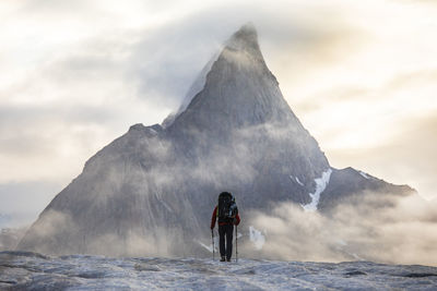 Rear view of man standing on mountain against sky