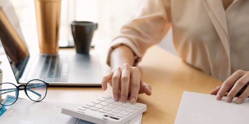 Midsection of woman using laptop on table