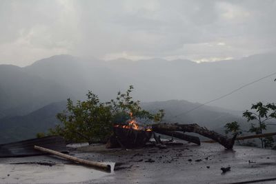 Burning fire pit on road against mountains during foggy weather