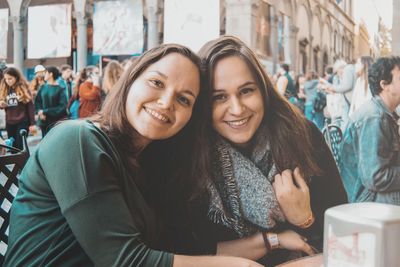 Portrait of smiling young friends sitting in city