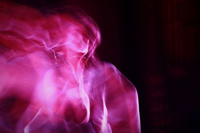 Digital composite image of woman in pink light against black background