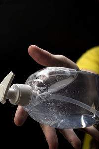 Close-up of hand holding glass against black background