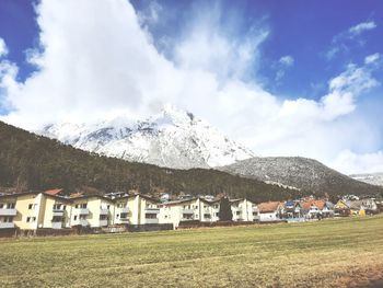 Scenic view of houses by snowcapped mountains against sky