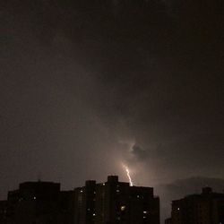 Low angle view of illuminated cityscape against sky at night