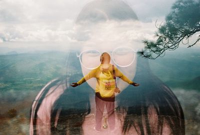 Digital composite image of woman standing on mountain against sky