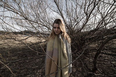 Portrait of woman standing amidst bare tree