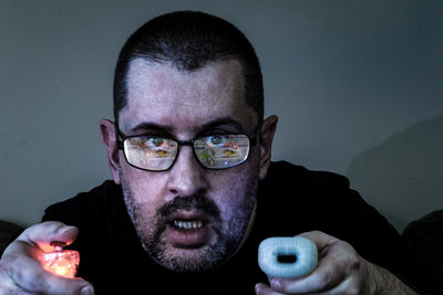 Close-up portrait of man playing video game at home