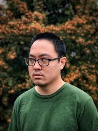 Portrait of young man looking away against blurred background of yellow berries.