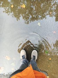 Low section of man standing on puddle