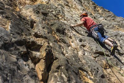 Low angle view of man climbing rock