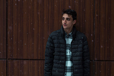 Portrait of young man standing against wall