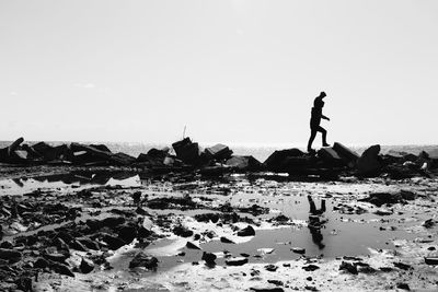 Silhouette of person carrying child on shoulders at jetty