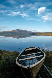 Boat moored on lake against sky