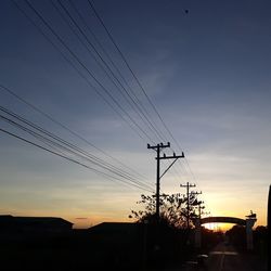 Silhouette of electricity pylon against sky during sunset