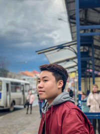 Portrait of young man looking away in city