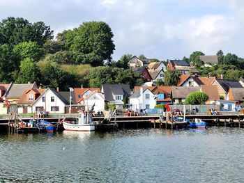 Houses by river and buildings against sky