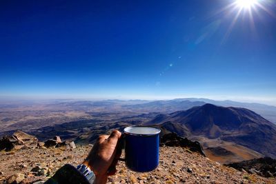 Man wearing sunglasses against mountain range against blue sky