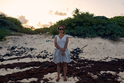 Portrait of young woman standing on land against sky