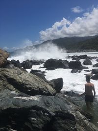 Sea waves splashing on rocks against sky