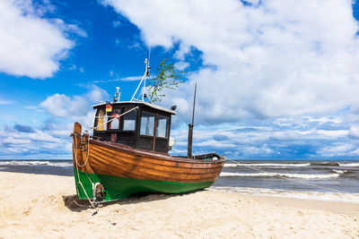 Fishing boat at beach against sky