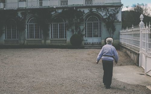 Rear view full length of senior woman walking in yard