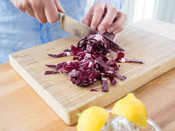 Midsection of man cutting red cabbage on table