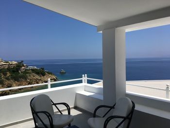 Railing by sea against clear blue sky seen from balcony